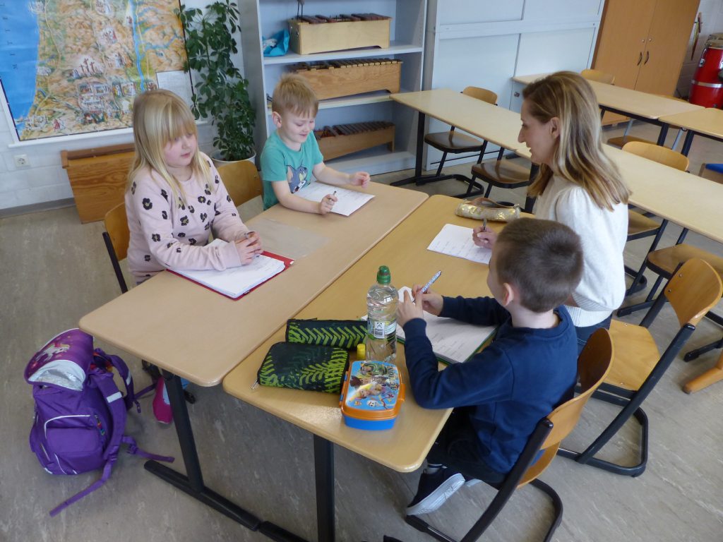 Kinder und Lehrer am Schultisch